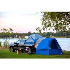 a truck parked next to a blue tent on the side of a body of water