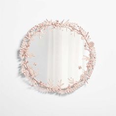 a round mirror with pink flowers on the side and a white wall in the background