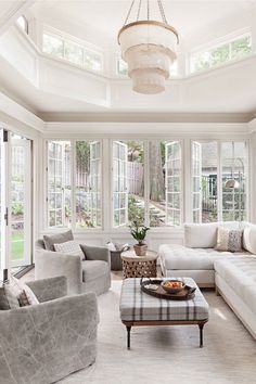 a living room filled with white furniture and lots of windows on top of each other