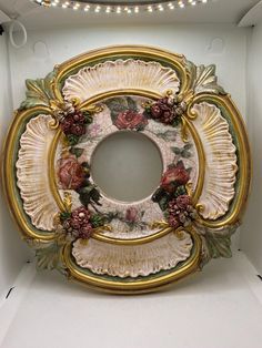 an ornately decorated mirror in a white box with lights on the ceiling above it