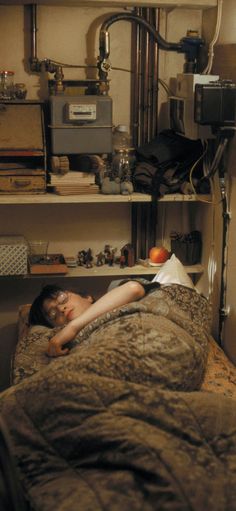 a woman laying on top of a bed next to a shelf filled with books and an apple