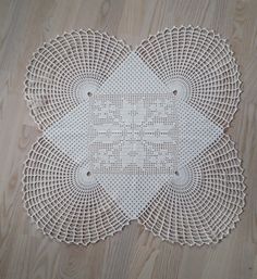 a white doily on a wood floor with two circles in the middle and one circle at the center