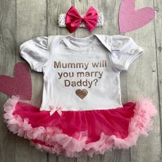 Such a Cute Way to Ask!!Short sleeve cotton soft Tutu romper with matching Bow and Headband Rose Gold Glitter lettering saying 'Mummy, will you marry Daddy?'Small Rose Gold glitter love heartAny questions or queries please just message me :) Cute Pink Onesie For Mother's Day, Pink Fitted Onesie For Birthday, Fitted Pink Onesie For Gift, Fitted Pink Onesie As A Gift, Fitted Pink Onesie Gift, Pink Fitted Onesie As A Gift, Pink Onesie With Letter Print As A Gift, Pink Onesie With Letter Print As Gift, Pink Cotton Bodysuit As Gift