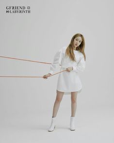 a woman in white is holding on to an orange string and posing for the camera