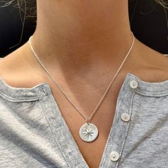 a woman wearing a silver necklace with a star charm on the back of her neck