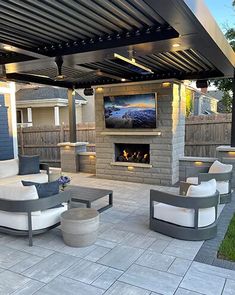 an outdoor living area with couches, tables and a television mounted to the wall