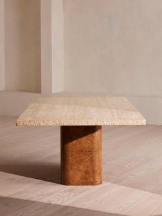 a wooden table sitting on top of a hard wood floor next to a white wall