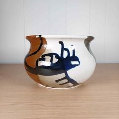 a white and brown vase sitting on top of a wooden table