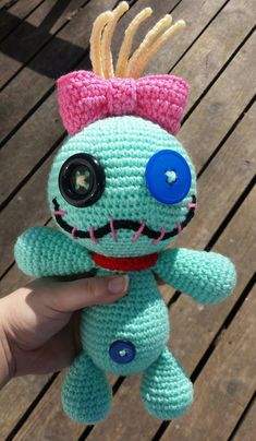 a crocheted stuffed animal with big eyes and a pink bow on its head