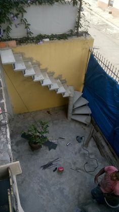 a man is working on some stairs in the back yard with plants and tools around him