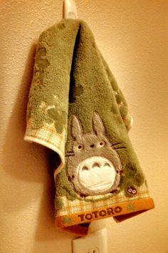 a towel hanging on the wall with a totoro drawn on it and a light switch