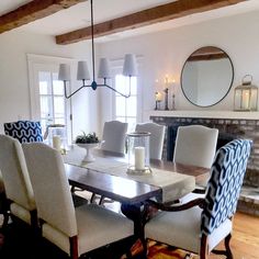 a dining room table with white chairs and a mirror on the wall above it,