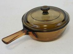 a brown pot with a wooden handle on a white surface