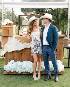 a man and woman standing next to each other in front of a cow stand with hats on