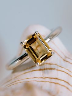 a yellow diamond ring sitting on top of a shell