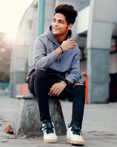 a young man sitting on top of a cement bench