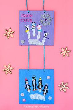 two handprinted pictures hanging from clothes pins on a pink background with snowflakes