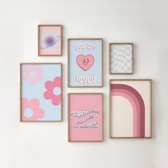 there are many framed pictures on the wall with pink and blue accents, including one that says you are loved