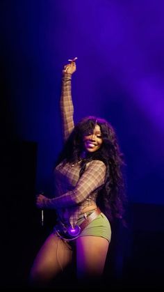 a woman is dancing on stage with her arms in the air