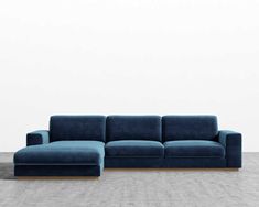 a large blue couch sitting on top of a wooden floor next to a white wall