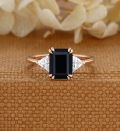 a black and white diamond ring sitting on top of a wooden table next to flowers