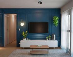 a living room with blue walls and white furniture in front of a flat screen tv