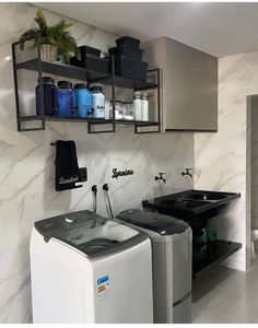 a washer and dryer in a room with marble walls, shelves above them