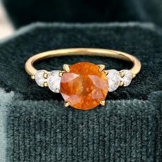 Sunstone Ring, 14k Solid Gold Ring, Orange Sunstone Ring with Moissanite, Engagement Ring, Gift For Her, Natural Sunstone Ring for Women  (in stock) - Metal: 14K Yellow Gold - Custom Color: Rose Gold, Yellow Gold, and White Gold  - Gross weight: 2.65g - Gold Weight: 2.49g - Gemstones: Sunstone, Moissanite - Sunstone CTW: 1.43(1pcs) - Sunstone size: 6.1 mm - Moissanite CTW: 0.80 (4pcs) - Ring size: 7 - Ring Width: 1.4mm - Ring Thickness: 1.4mm  - Ring Width: 20.67mm Approximately - Ring Height: 25.08mm Approximate Shipping It usually takes 2-3 weeks to make and 3-5 days to ship We apply a tracking number for every single package. Engraving You can order a custom engraving. (just contact me in advance) Orange Topaz Round Ring For Anniversary, 14k Gold Orange Rings With Accent Stones, Orange Diamond Rings With Prong Setting, Orange Topaz Anniversary Ring, Orange 14k Gold Rings With Accent Stones, Orange Sapphire Wedding Ring, Orange Sapphire Round Ring, Orange Diamond Ring With Prong Setting For Anniversary, Orange Ring With Center Stone For Anniversary