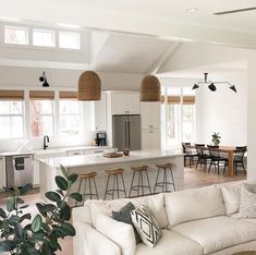 a living room filled with furniture next to a kitchen and dining room table covered in lots of windows