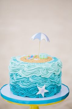 a cake with blue frosting and an umbrella on top