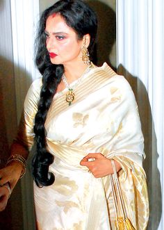 a woman with long black hair wearing a white sari and carrying a yellow purse