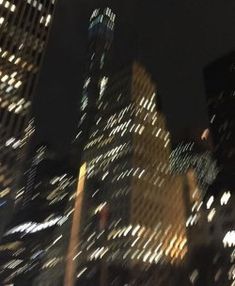 the city skyline is lit up at night with skyscrapers in the foreground and street lights on either side