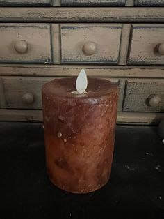 a candle sitting on top of a table next to drawers