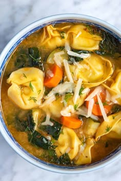 a bowl of tortellini soup with carrots, spinach and parmesan cheese