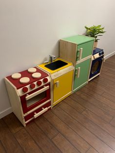 an assortment of colorful play kitchen sets on the floor in front of a white wall