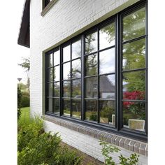 a white brick building with black windows and plants