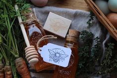 some honey and carrots on a table next to an egg, beehive, and parsley