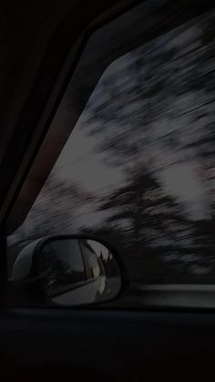 the rear view mirror of a car with trees in the background