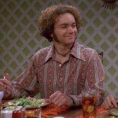 two men sitting at a table with plates of food and drinks in front of them