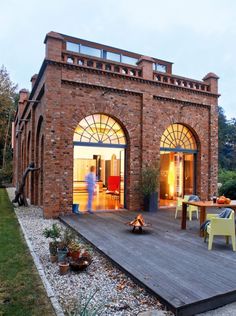 a brick building with an open patio and dining area in the back ground, surrounded by grass