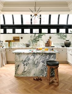 a kitchen with marble counter tops and stools next to an island in the middle