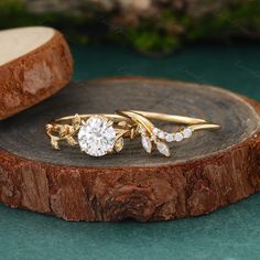 two gold rings with diamonds sitting on top of a tree stump next to another ring