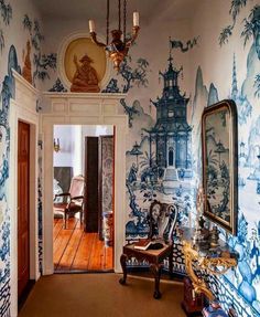 the hallway is decorated with blue and white wallpaper, an ornate chandelier and antique furniture