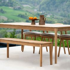 a wooden table with two benches next to it and an orange bowl on the table