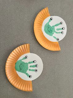 two paper plates with handprints on them sitting next to each other in front of a gray surface