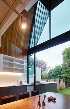 a wooden table sitting in front of a window filled with lots of glass doors next to a kitchen