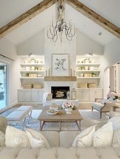 a living room filled with white furniture and a chandelier hanging from the ceiling