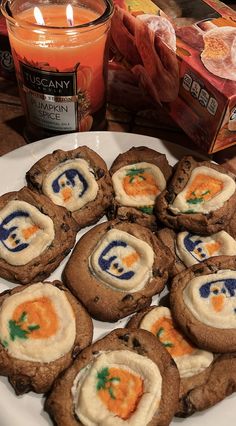 cookies with cream cheese and carrots are arranged on a plate next to a candle