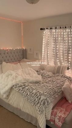 a large bed sitting in the middle of a bedroom next to a window with lights on it