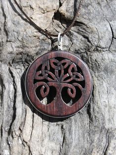 This intricate carving of the Celtic tree of life will be made for you, or a loved one, in my studio on the West of Ireland. Encircled into a side groove with a sterling silver ring, this delicately carved Tree necklace features a piece of rosewood, recycled from guitars constructed by a local luthier. As a musician myself, I take enormous satisfaction in creating a piece of jewelry whose inherent wood has previously featured in a beautiful hand-made guitar. Also, part of rosewood's attractivene Traditional Brown Carved Jewelry, Spiritual Wood Jewelry For Gifts, Artisan Carved Jewelry For Meditation, Traditional Brown Engraved Jewelry, Traditional Handmade Wooden Jewelry, Brown Carved Round Pendant Necklace, Artisan Wooden Jewelry As A Gift, Bohemian Carved Brown Jewelry, Artisan Carved Brown Jewelry